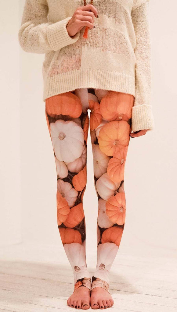 Front view of model wearing white and orange pumpkin leggings