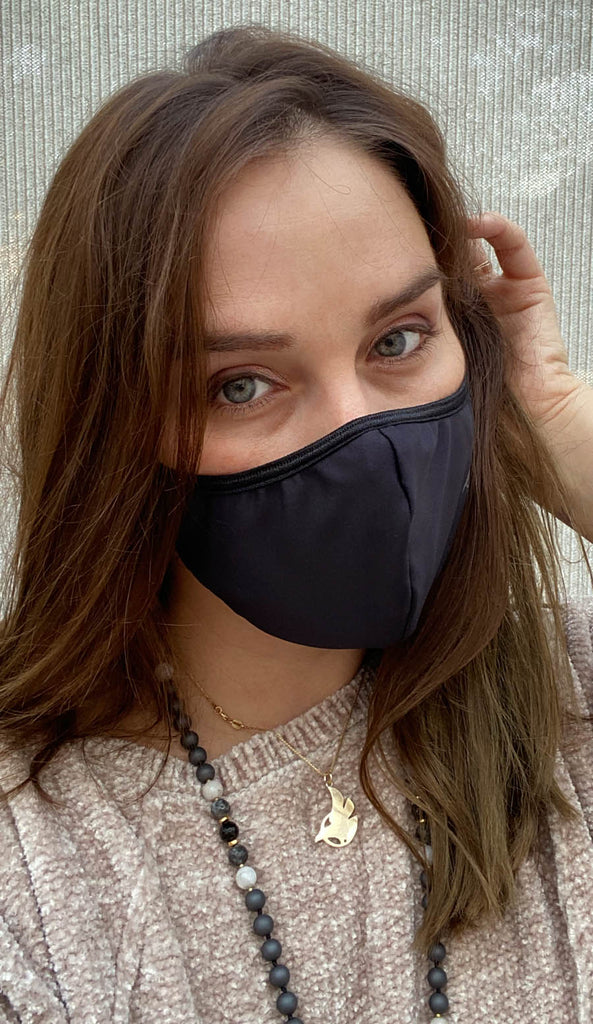 Girl wearing black face mask with silver trim logo and adjustable ear loops