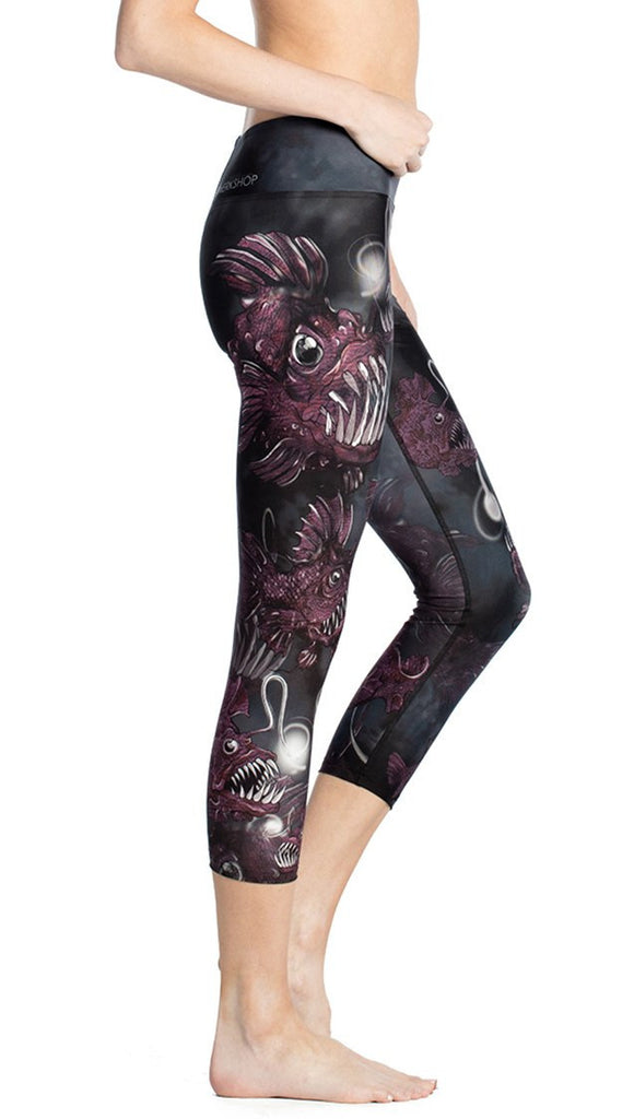 close up side view of model wearing deep sea angler fish printed capri leggings