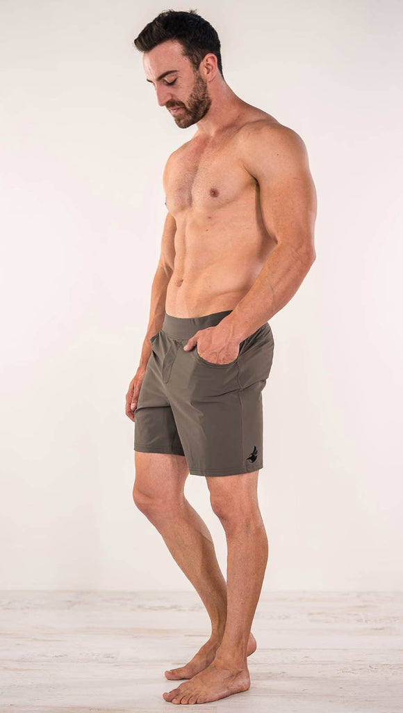 Left side view of model wearing men's taupe performance shorts with slim fit