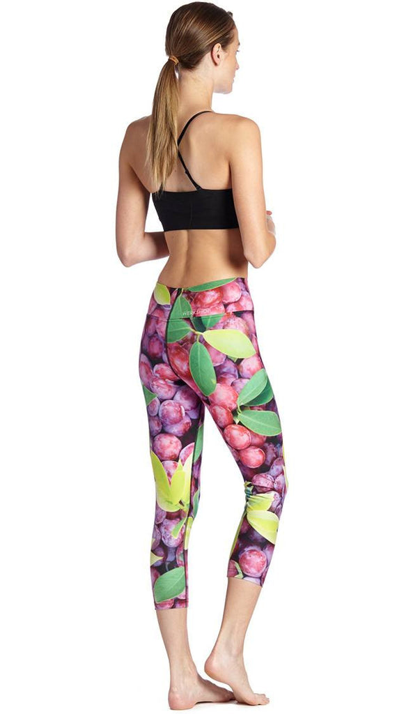 back view of model wearing grapes and leaves themed printed capri leggings